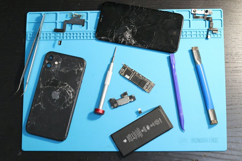 Celular desmontado sobre a bancada, com ferramentas